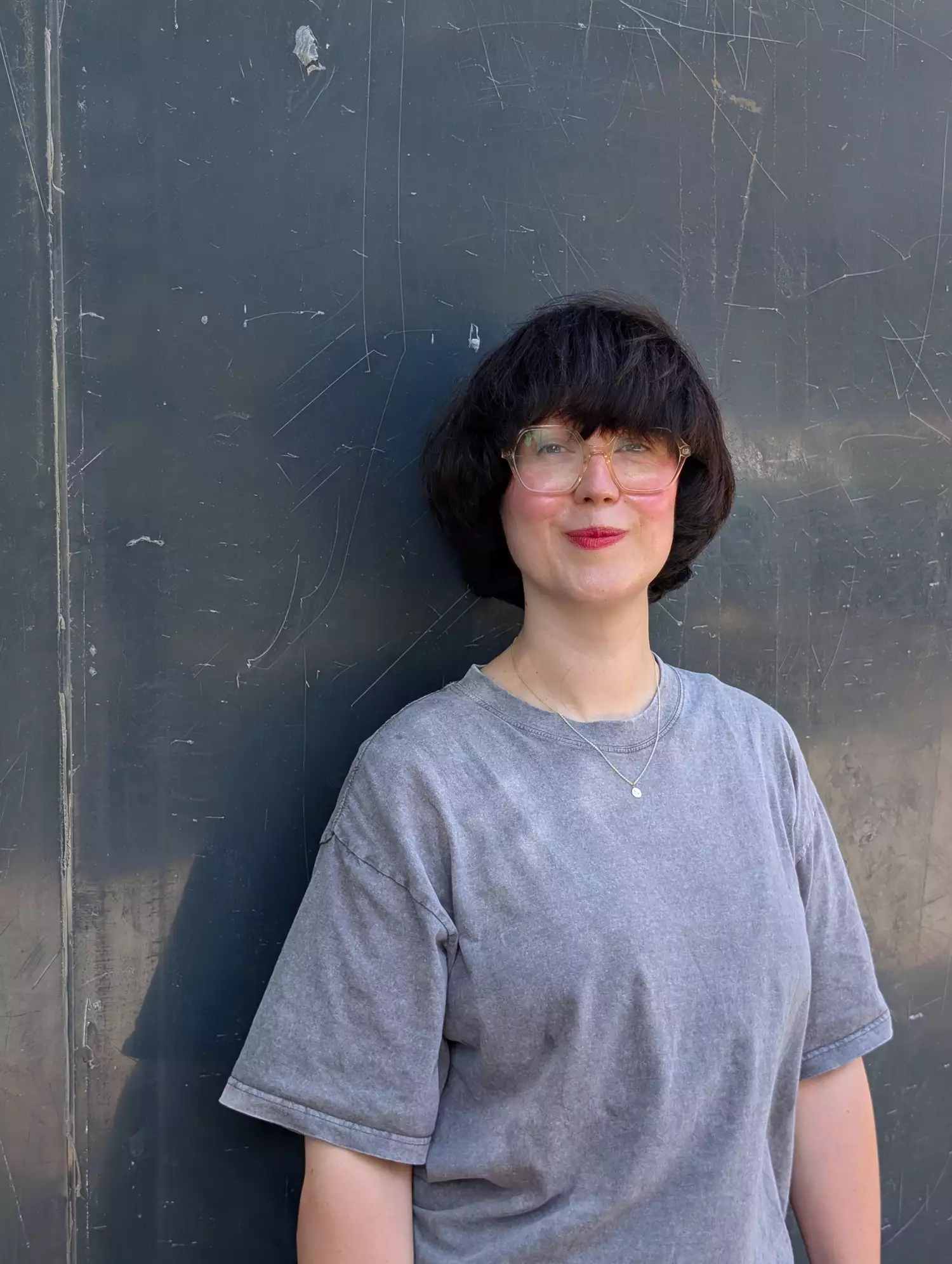 Jen Malarkey wearing a grey t-shirt stood against a metal background