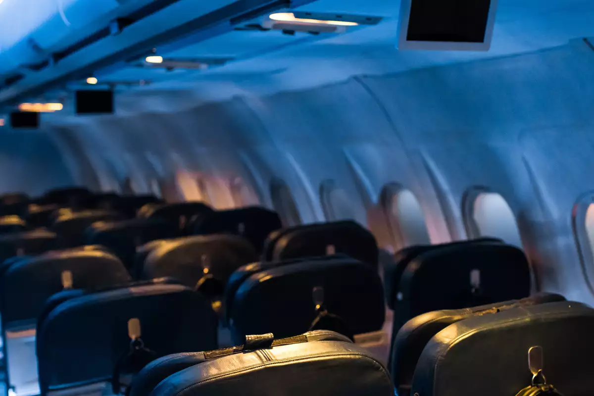 The inside of an aeroplane cabin as part of the FLIGHT experience. The lighting is blue.