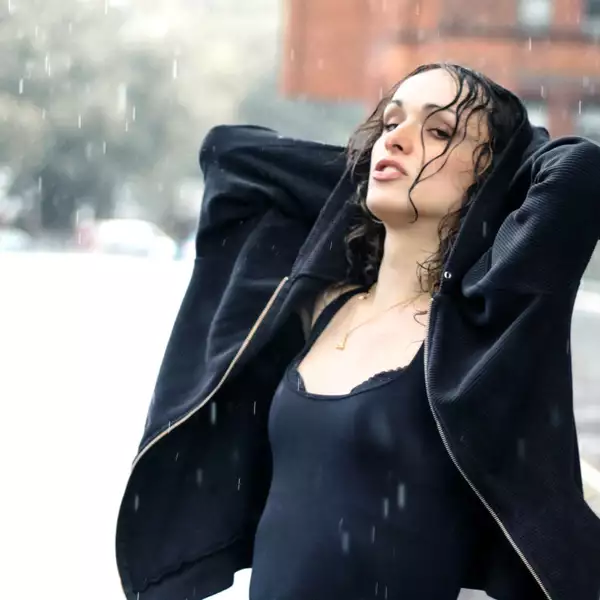 Phia Sky stood on a street outside with their arms behind their head