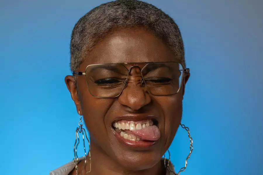 DJ Paulette wearing big hoop earrings on a bright blue background