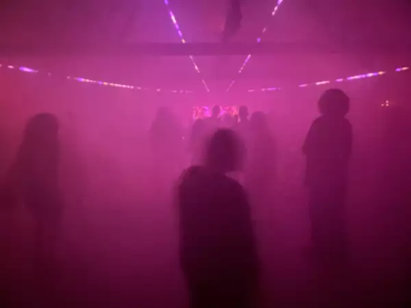 Figures on a dancefloor bathed in pink light