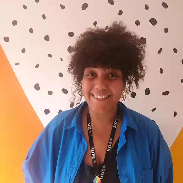 Headshot of Abi Clarke against a colourful wall