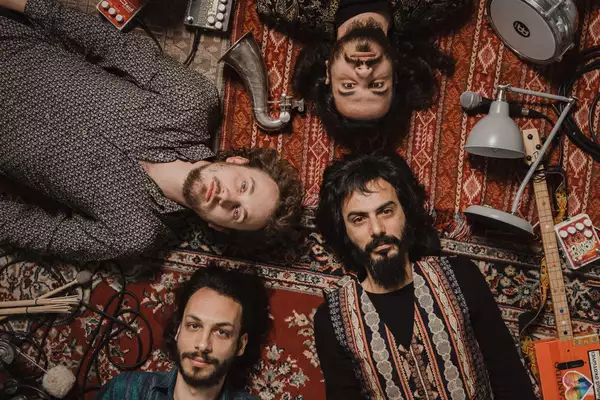 The four members of Buzz’ Ayaz lying on patterned rugs on the floor, surrounded by instruments and equipment
