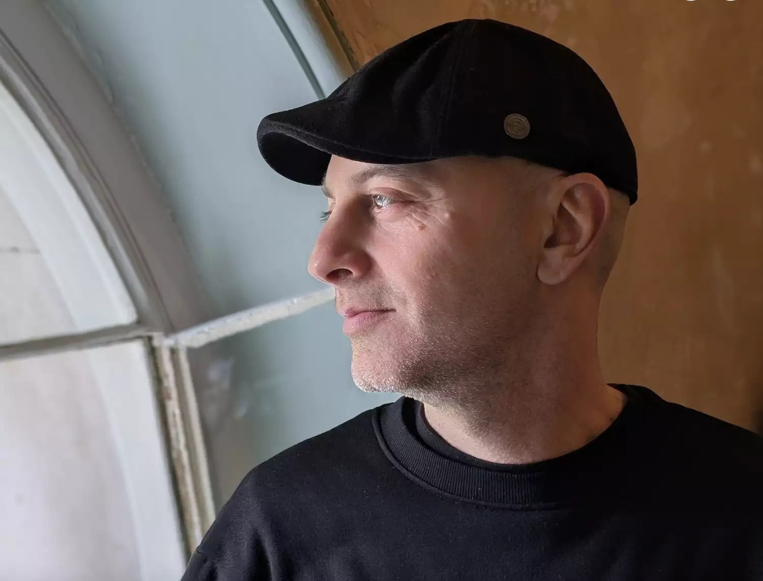 Headshot of Omid Asadi looking out a window with a black hat