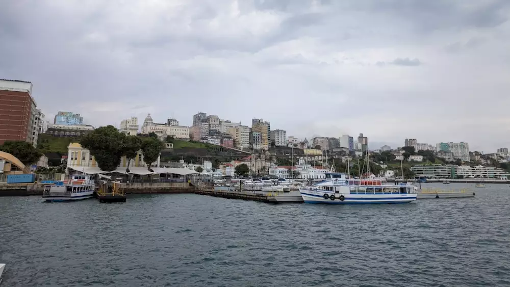 Photo taken from a boat, showing the sea, boats and the coastline in Bahia, Brazil