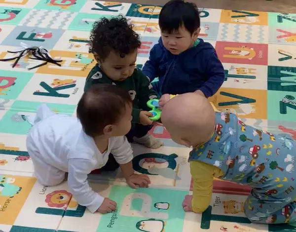 Four babies playing on a mat decorated with the alphabet