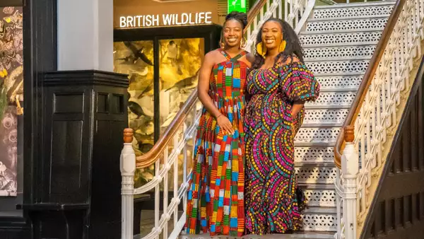 Adeola and Ronke Jane Adelakun smiling, wearing colourful dresses in a Museum setting