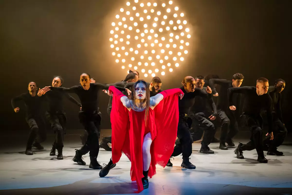 Dancer wearing a red dress surrounded by dancers in black clothing in Free Your Mind