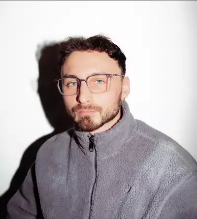 Arif True wearing a fluffy grey adidas fleece on a white background