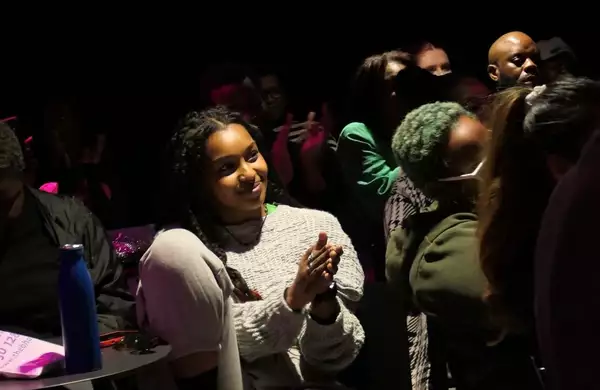 A person clapping and smiling in the audience. They are looking off-centre to the side.