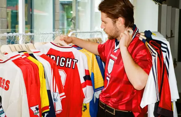 A person browses through a selection of vintage football shirts