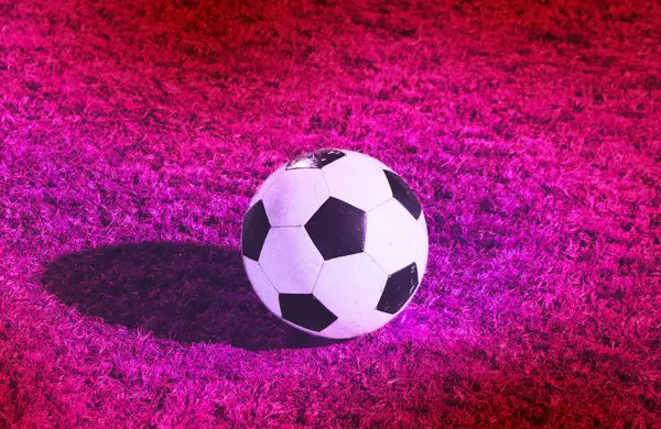 A football on a bright pink football pitch