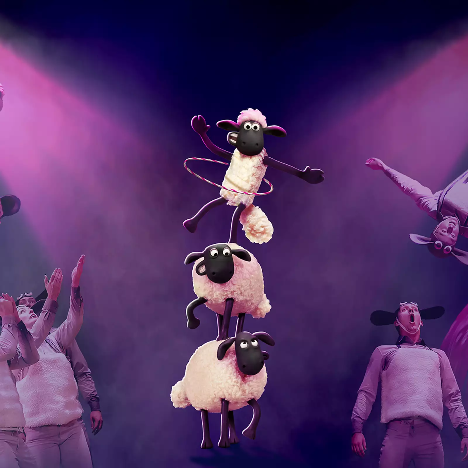 Performers in sheep costumes execute acrobatic stunts and aerial silk acts under dramatic pink lighting. In the center, three animated sheep from "Shaun the Sheep" balance in a tower, with the top one hula-hooping.
