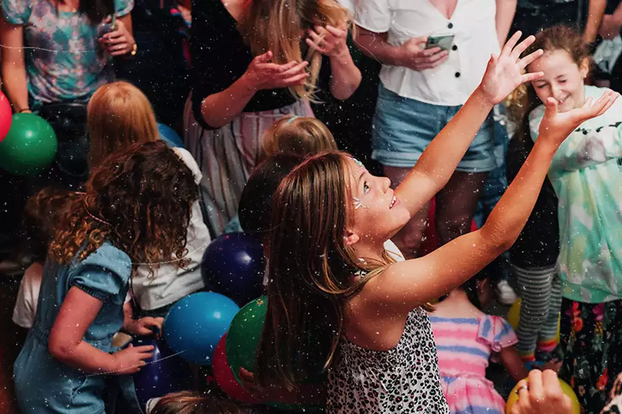 A child throwing a balloon in the air – surrounded by other children and balloons