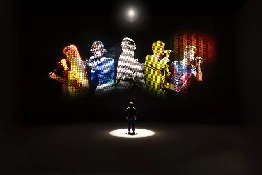 A person looking at five versions of David Bowie singing on a large screen