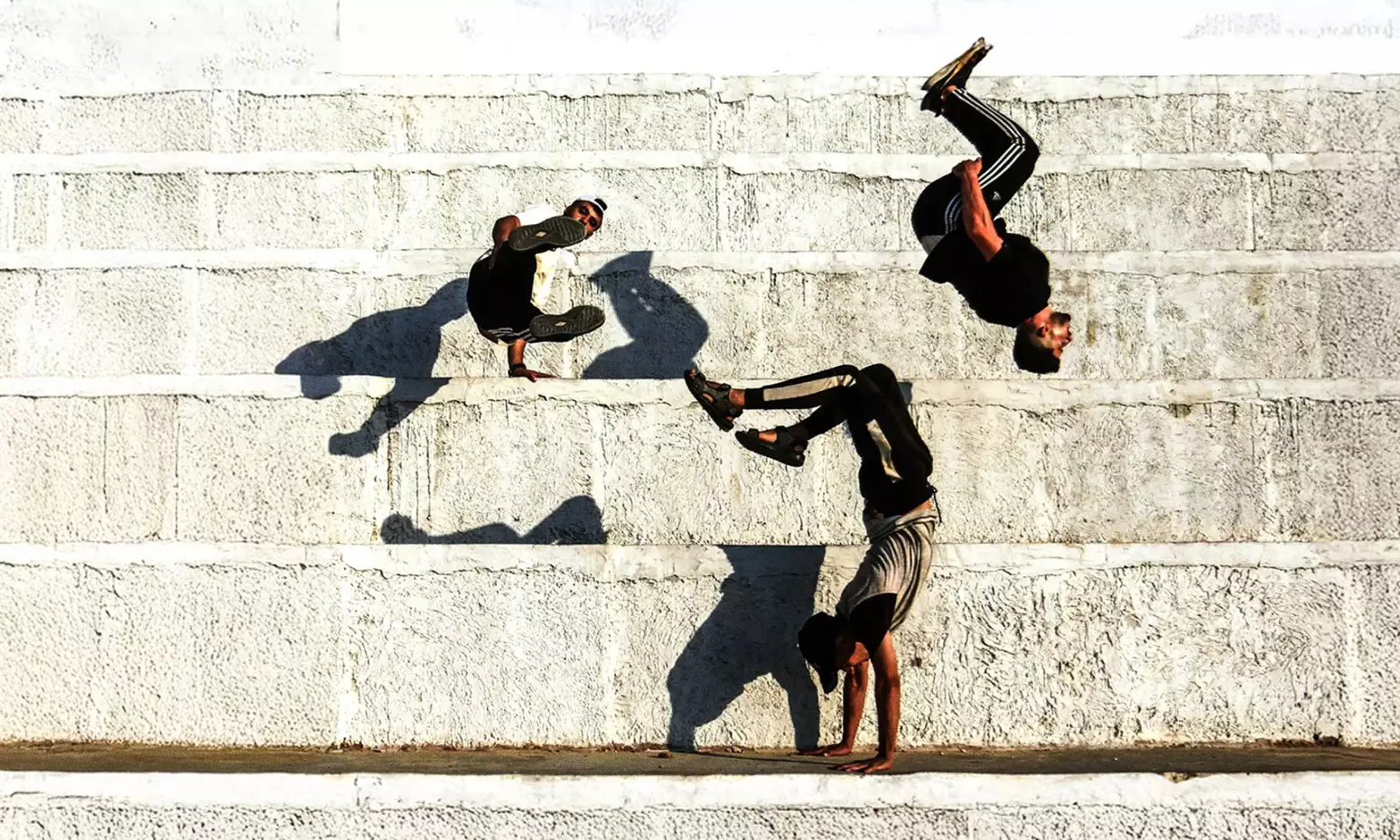 three people doing backflips against a wall