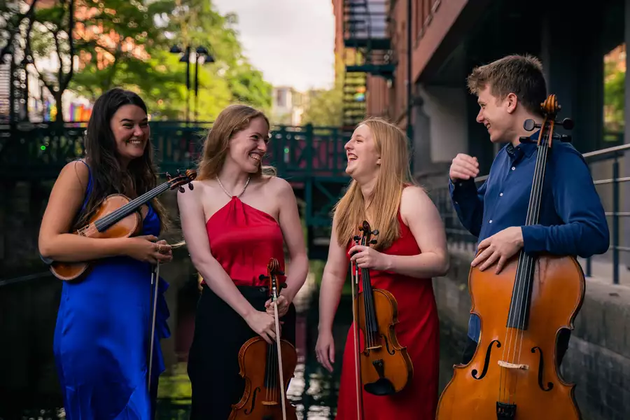 The Innsaei String Quarter stand in front of a canal in brightly coloured clothing