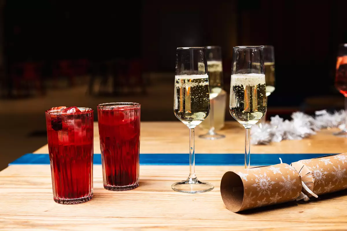 Two red cocktails, two glasses of Prosecco and a Christmas cracker on a table