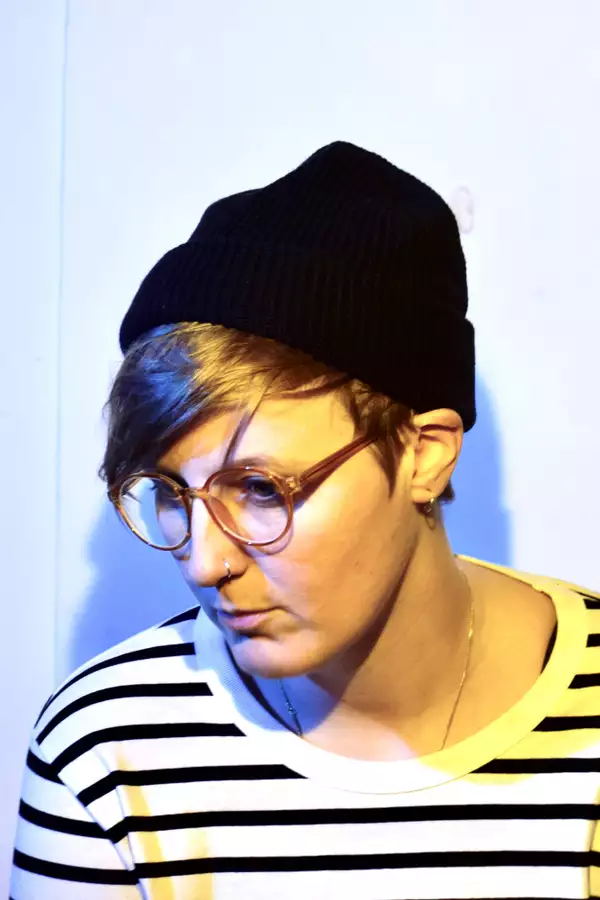 Alexandra Faye Braithwaite in a black beanie, glasses and striped t-shirt