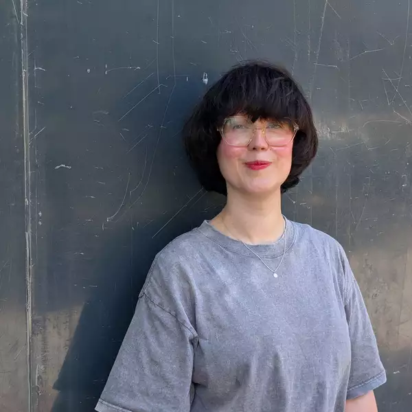 Jen Malarkey wearing a grey t-shirt stood against a metal background