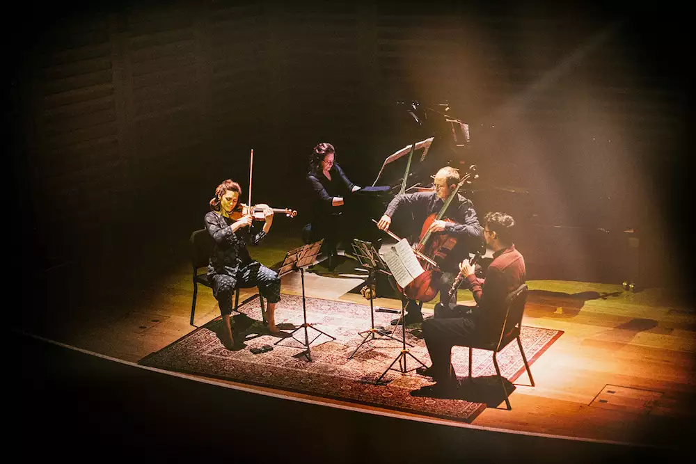Four musicians from Manchester Collective performing on stage on a carpet