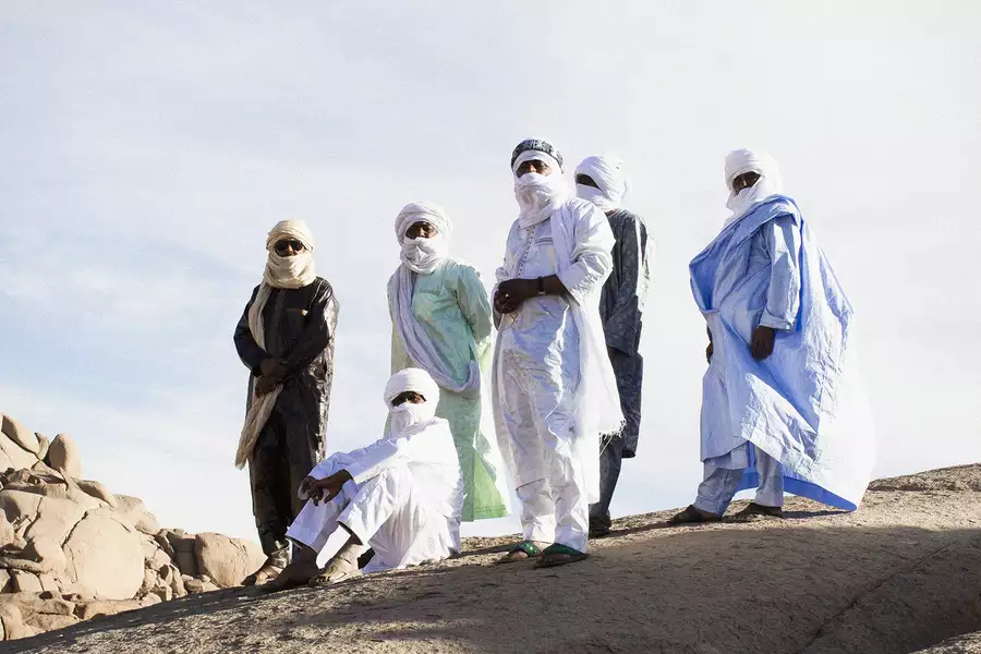 Members of Tinariwen stood on a large rock in the sunshine