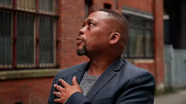 Headshot of Levi Love stood outside in front of a brick wall, looking to the left