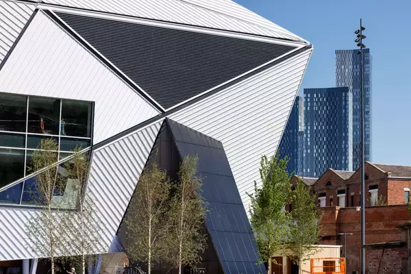 The side of Aviva Studios on a sunny day, with the skyscrapers behind