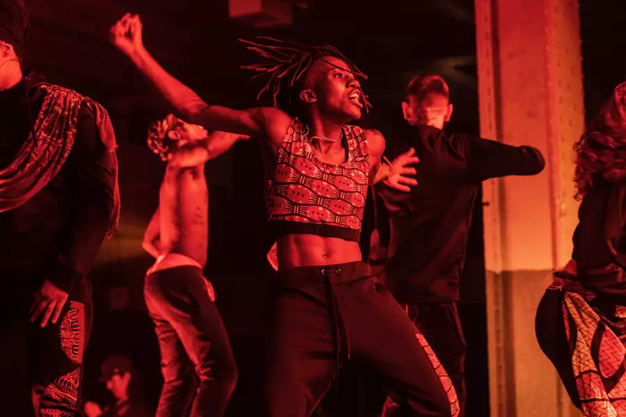 Dancers performing on stage. The image has a red hue.