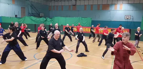 A group of people doing a qigong class in a sports hall