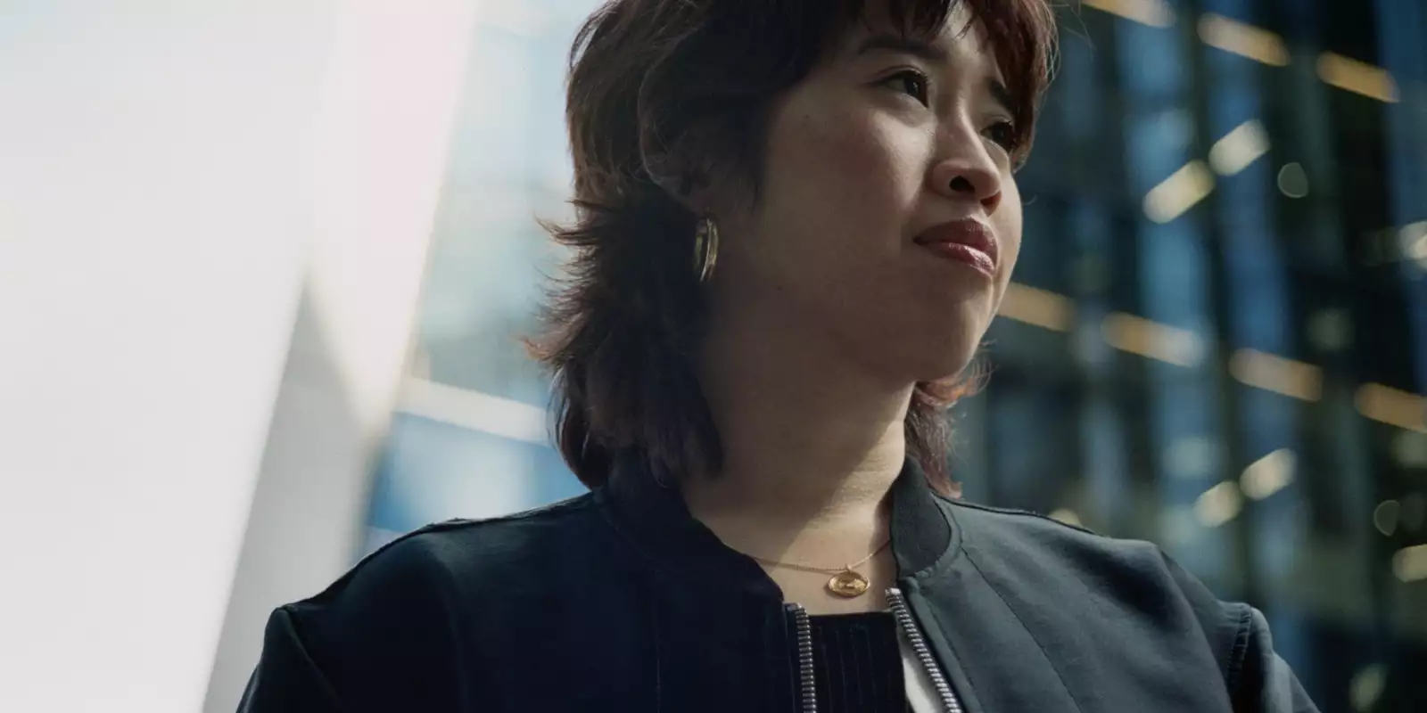 Headshot of Zing Tsjeng with a blurred glass building in the background