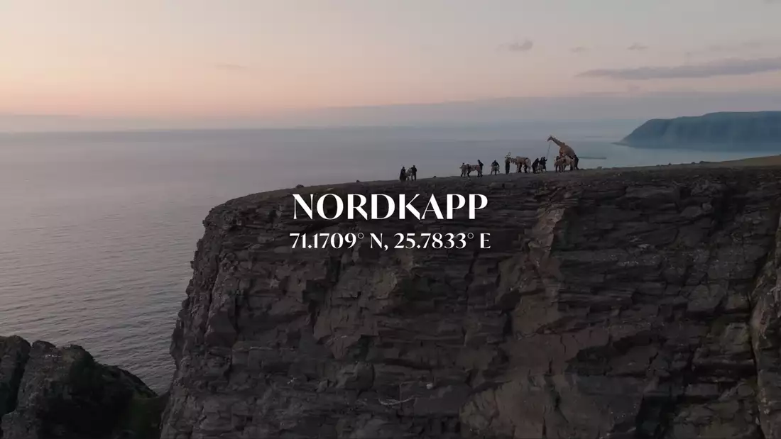 Cliffside view at Nordkapp with people and the Herds under a pastel sunset sky, text reads: “NORDKAPP 71.1709° N, 25.7833° E”.