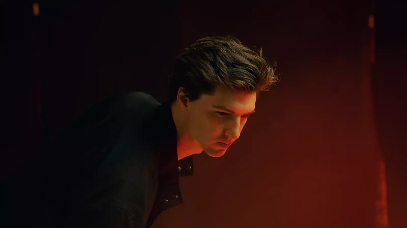 Luke Mombrea wearing a black shirt on a red background