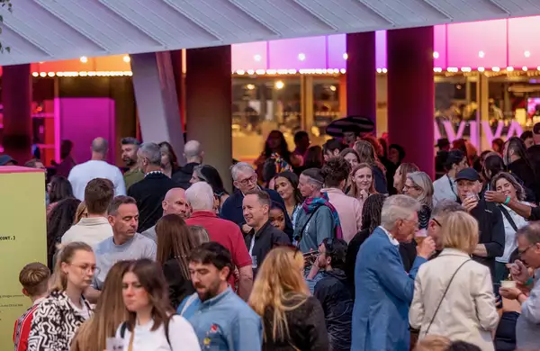 A large crowd of people chatting, drinking and sitting on Festival Square
