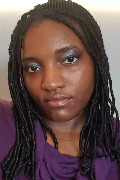 Square headshot of Anita Ezeh wearing a purple top and glittery eyeshadow