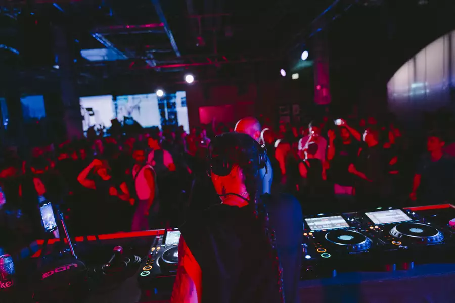 A person DJing in the Social with red lighting and people dancing