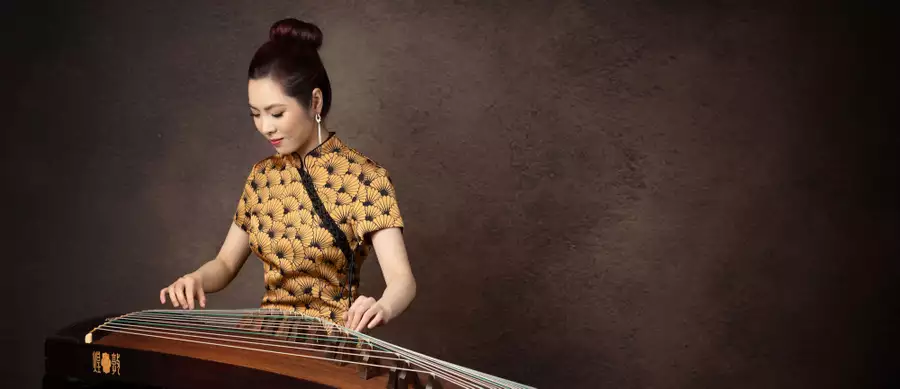Belle playing the guzheng – against a brown background