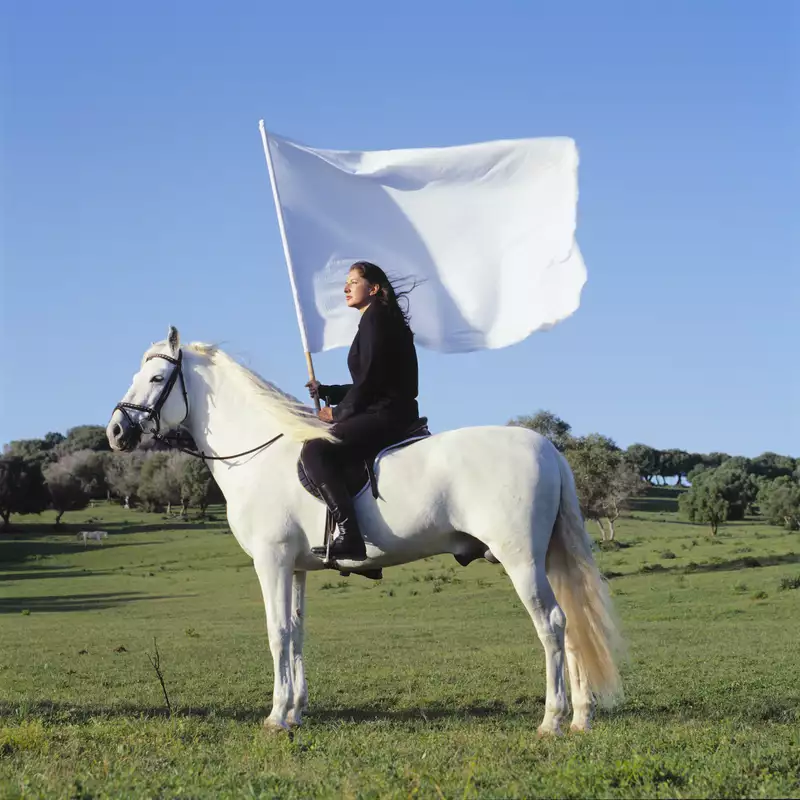 Marina Abramović on a white horse holding a white flag