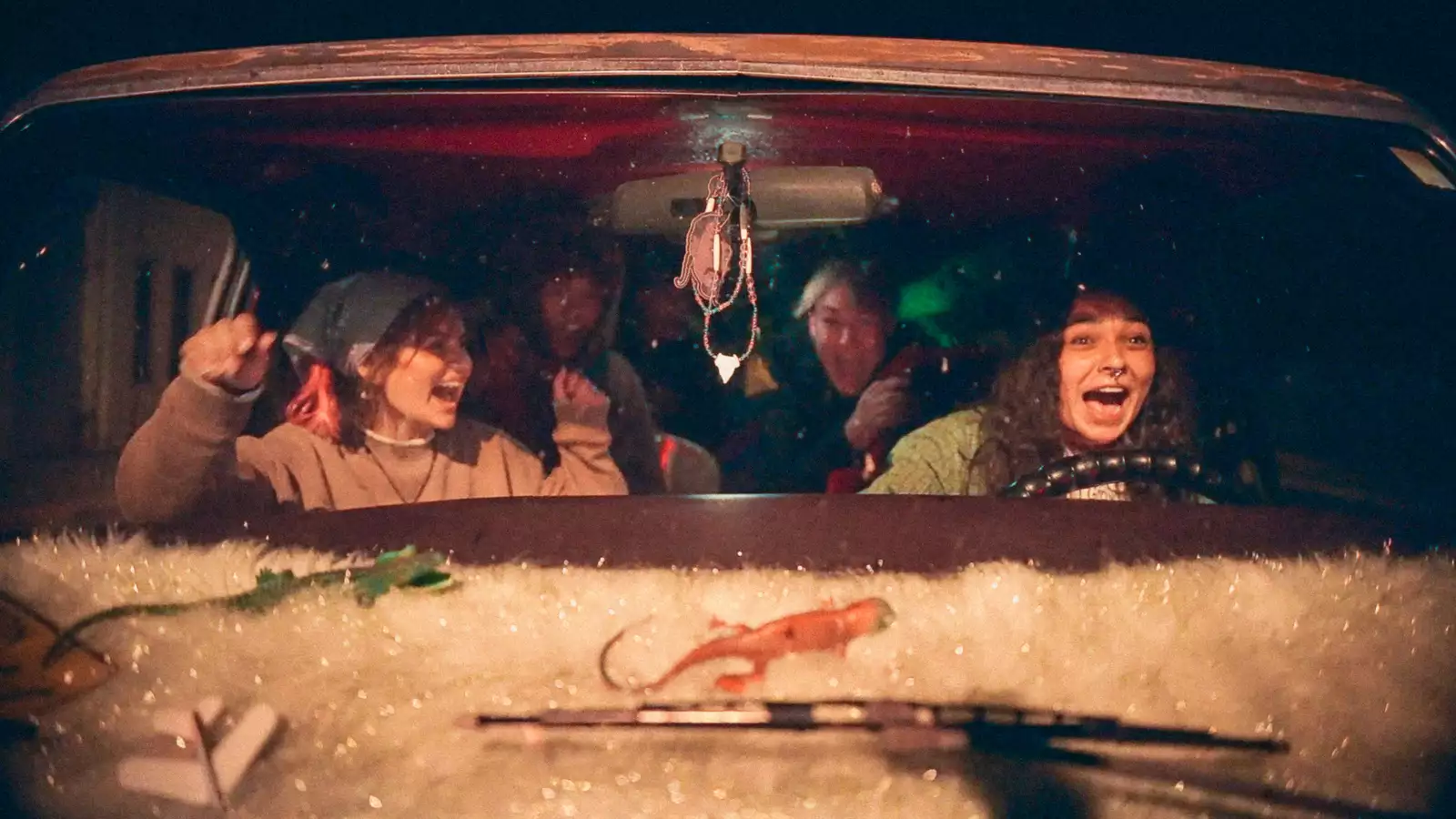 Still from Gasoline Rainbow. Shot of young people through the front windscreen of a van. They are screaming and laughing whilst one drives.