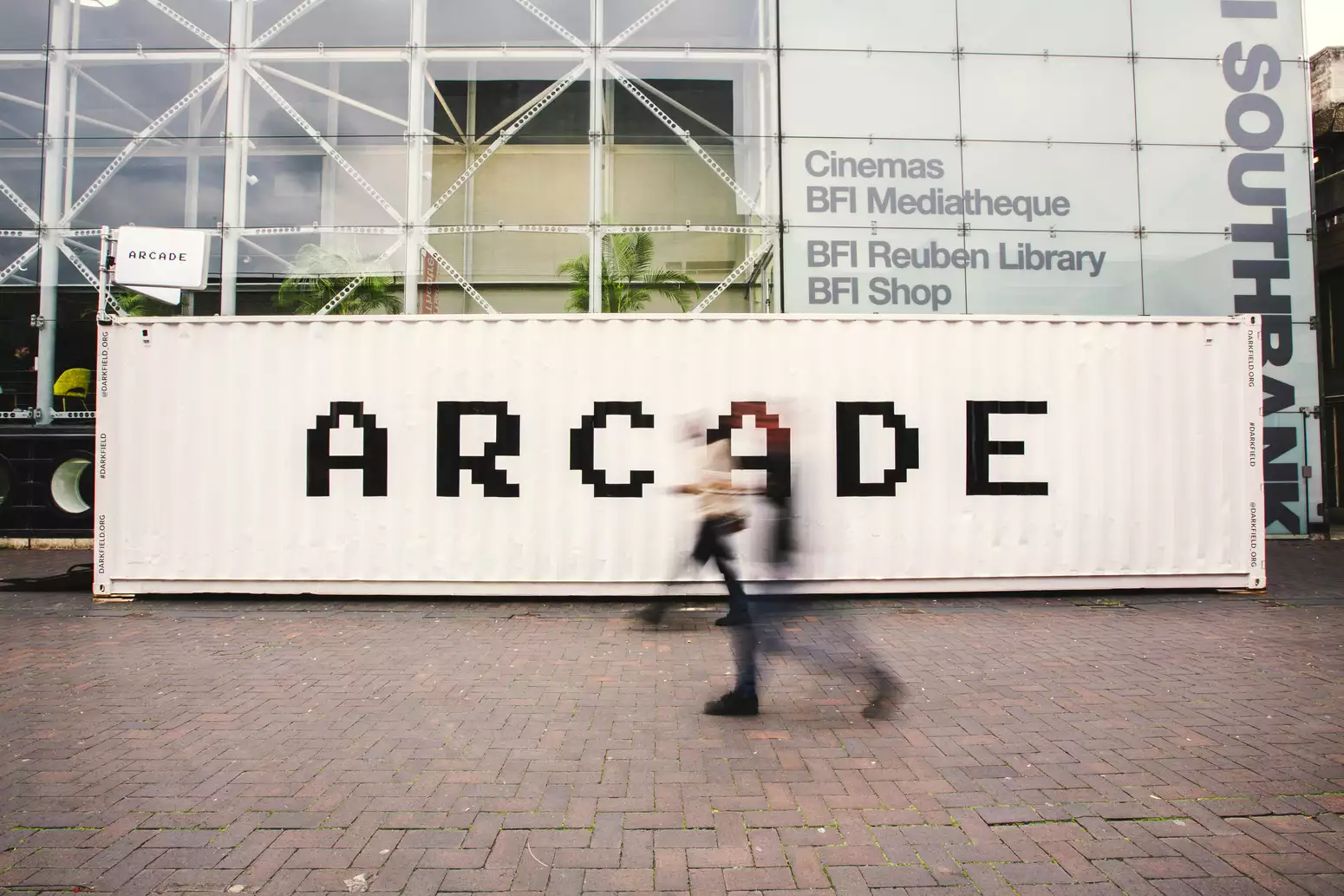 The Darkfield shipping container containing the experience ARCADE. The container is outside, pained white, with the word 'ARCADE' in black text.