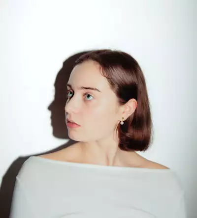 Honor Rowlands wearing a white top, looking to the side, on a white background