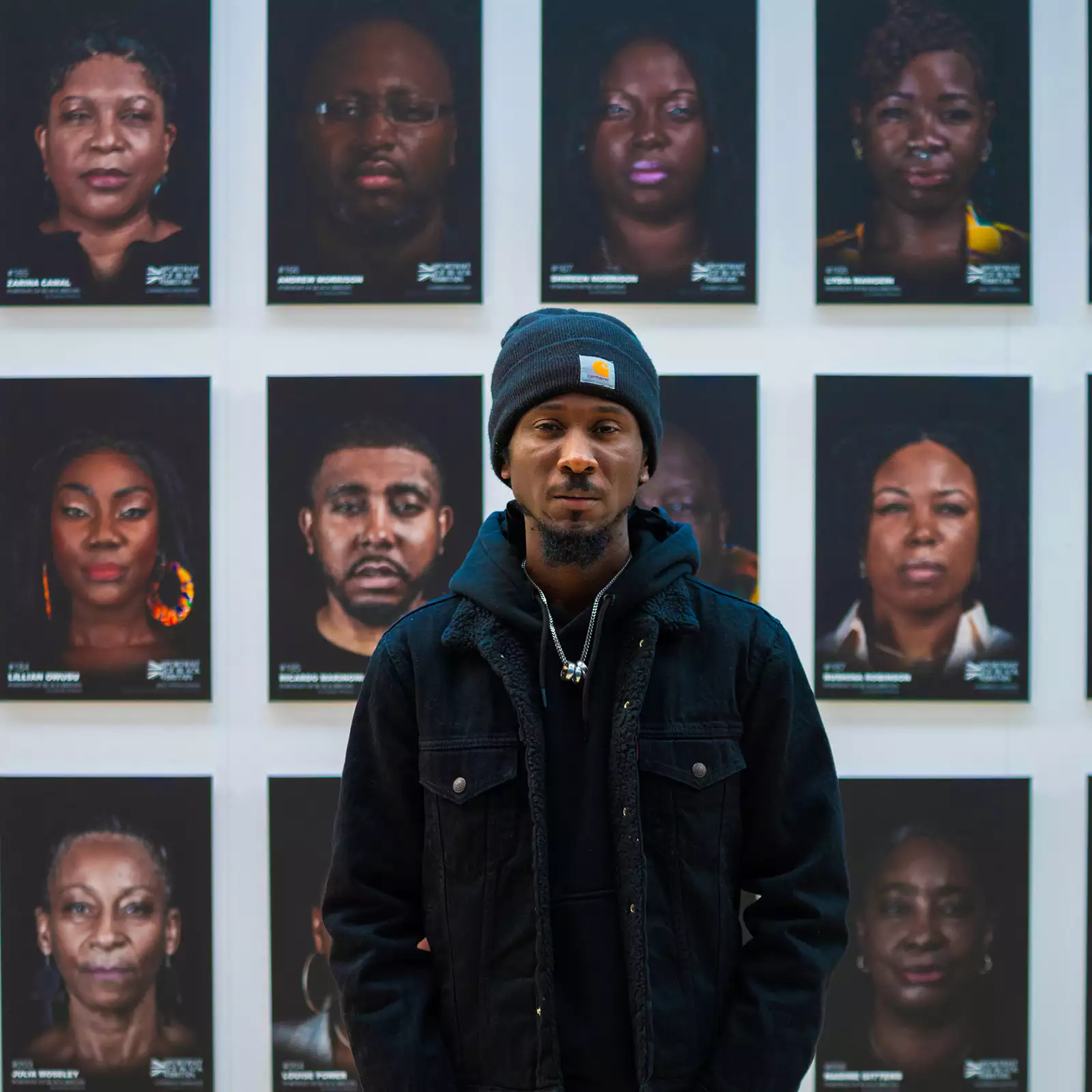 Cephas Williams stood in front of a wall of his portraits