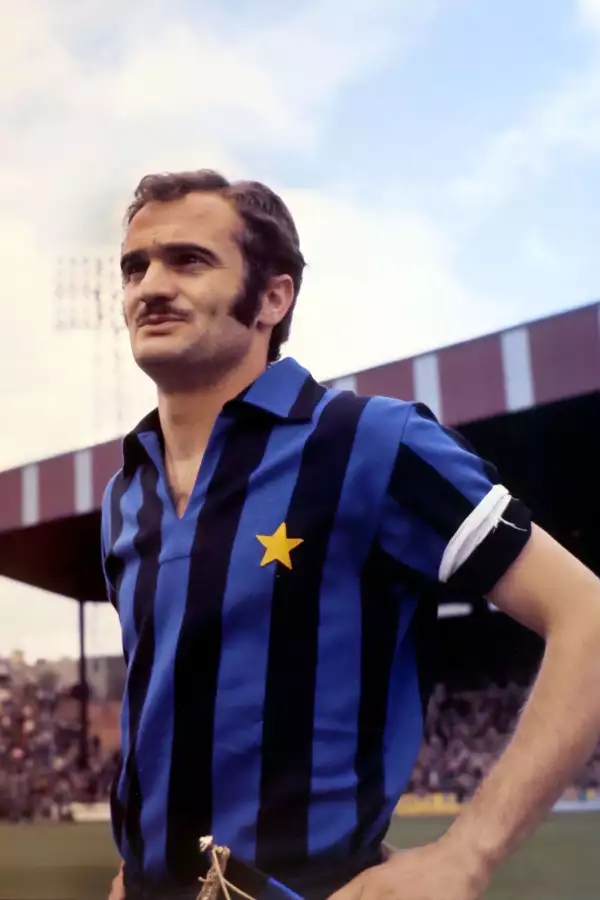 Sandro Mazzola stood on an outdoor pitch wearing a blue and black striped kit