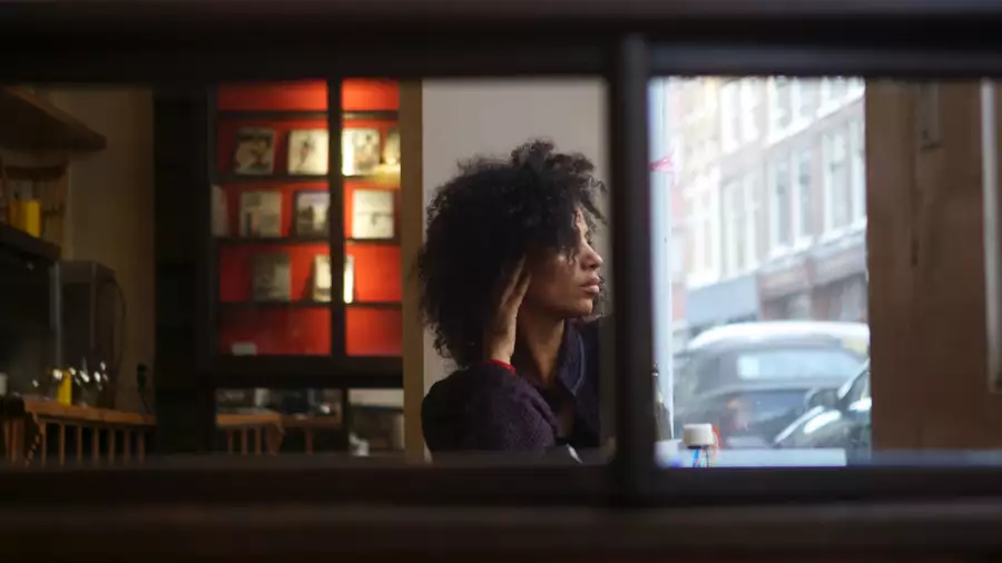 Juliet Ellis inside a dark bar, looking out the window at the street outside.