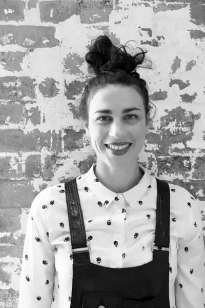 Black and white headshot of Libby McDonnell smiling against a brick wall