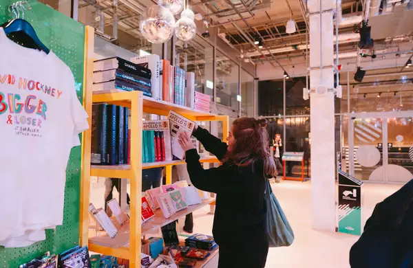 A person looking through some books in the shop at Aviva Studios with glitter balls above their head