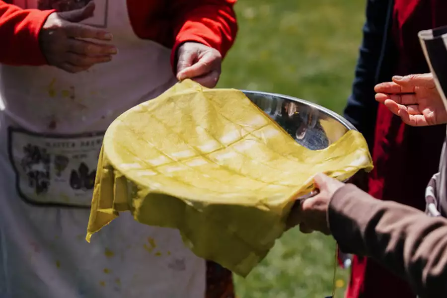 Two people holding a yellow tie-dye cloth