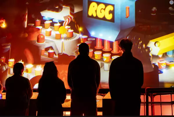 Silhouettes of people in front of a wall of digital art