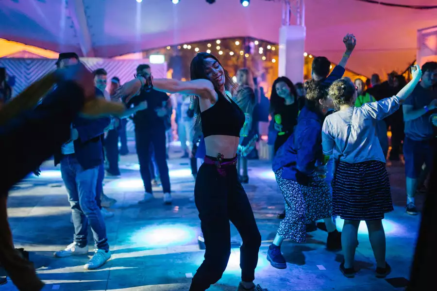 A girl dancing at festival square surrounded by people on the dancefloor