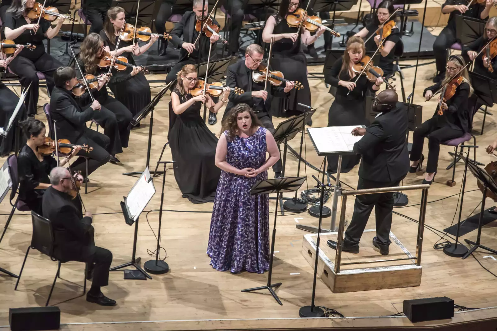 Photo of a soloist in a purple dress singing with the orchestra